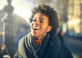 Smiling young woman enjoying music in urban Budapest setting. Vibrant and joyful moment.